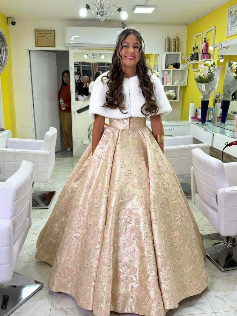 Quinceañera con vestido dorado y capa